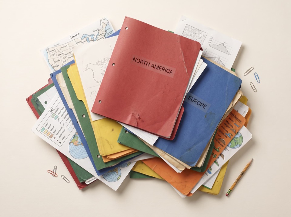 A stack of worn school folders labelled North America and Europe